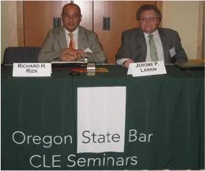 Rizk seating on Oregon State Bar CLE Seminars table